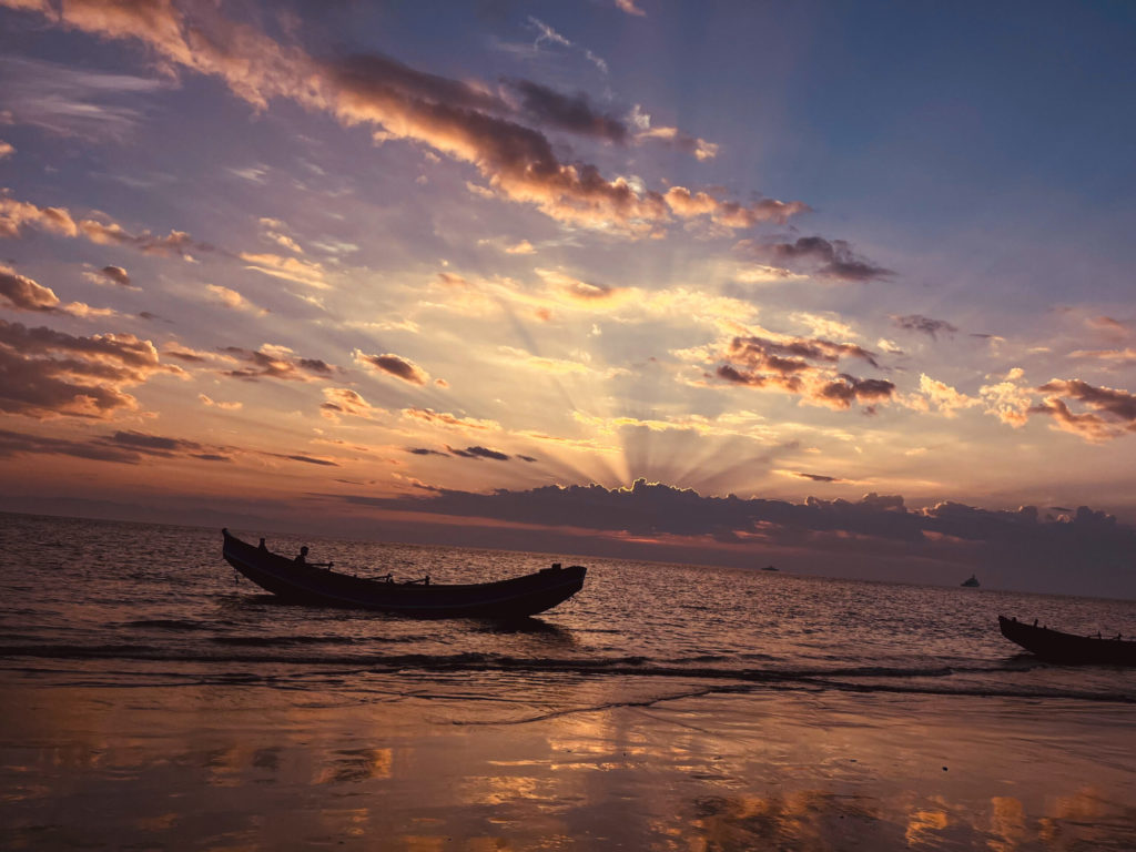 Boy in a boat on a Bangladesh beach at sunset.